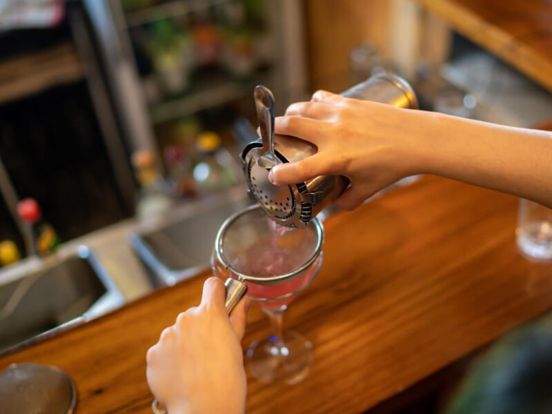 A closeup of a drink being poured into a glass at a cocktail making class.